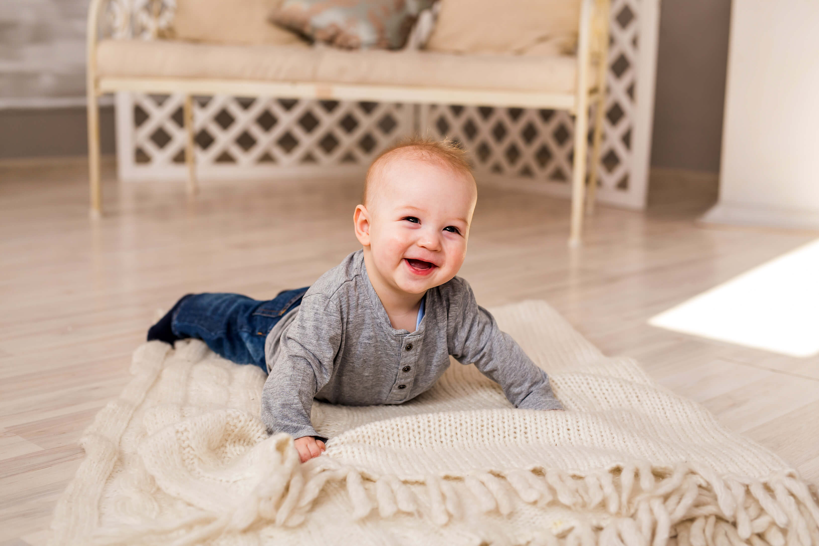 lachendes Baby in babysicherer Wohnung auf beiger Decke