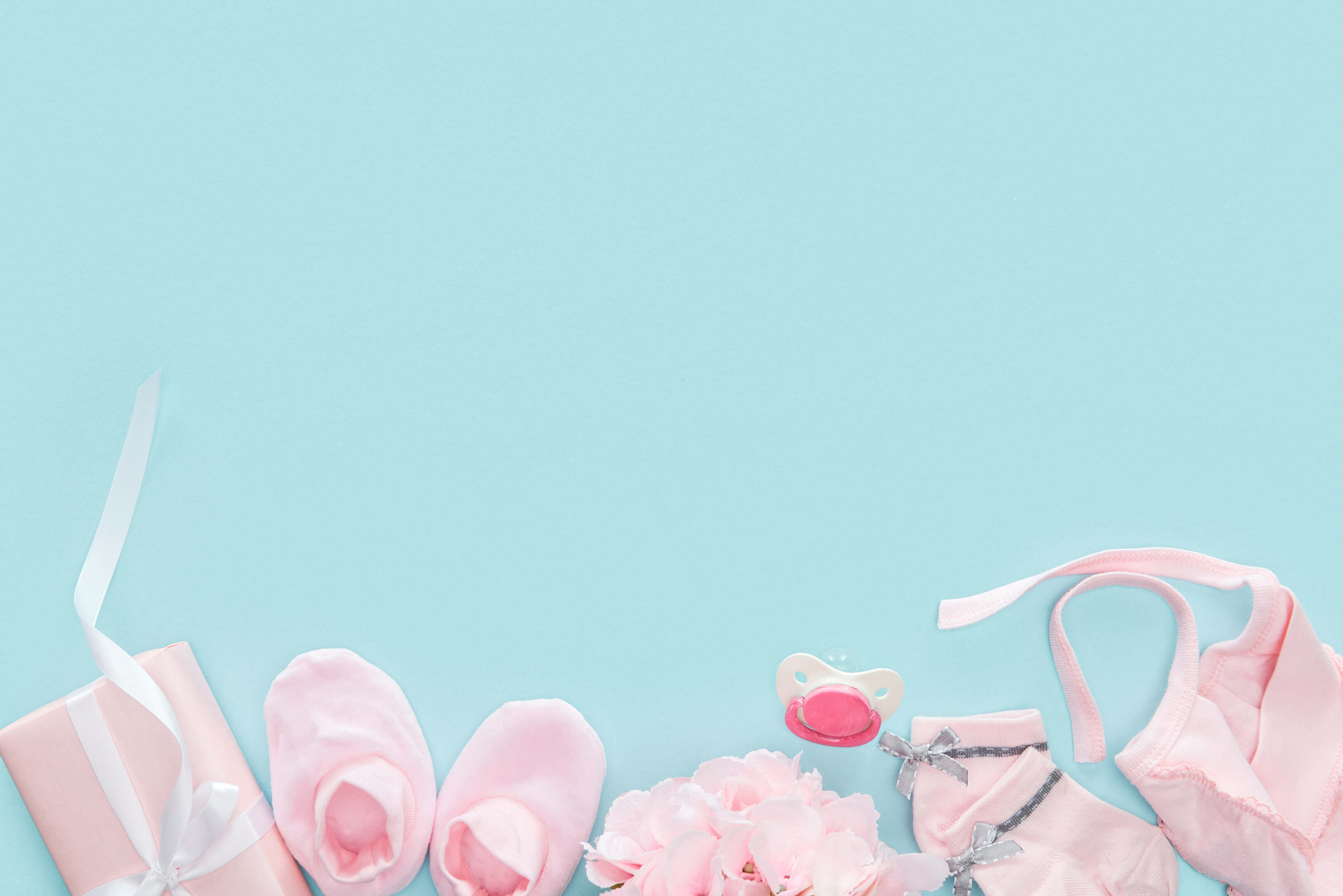 rosa Geschenke zur Geburt fürs Baby vor blauem Hintergrund