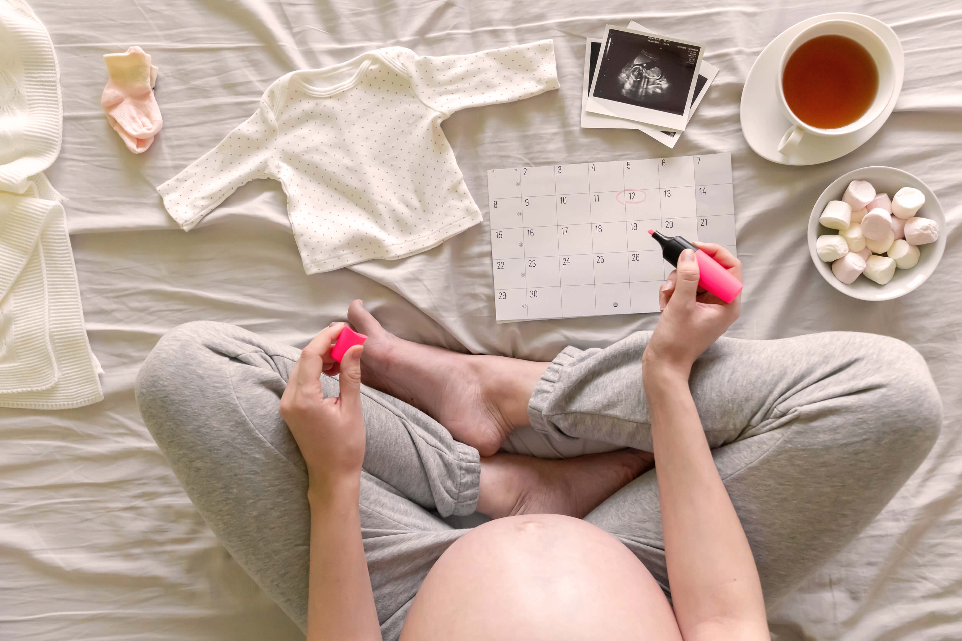 Schwangere mit Kalenderund Babysachen, Geburtstermin berechnen