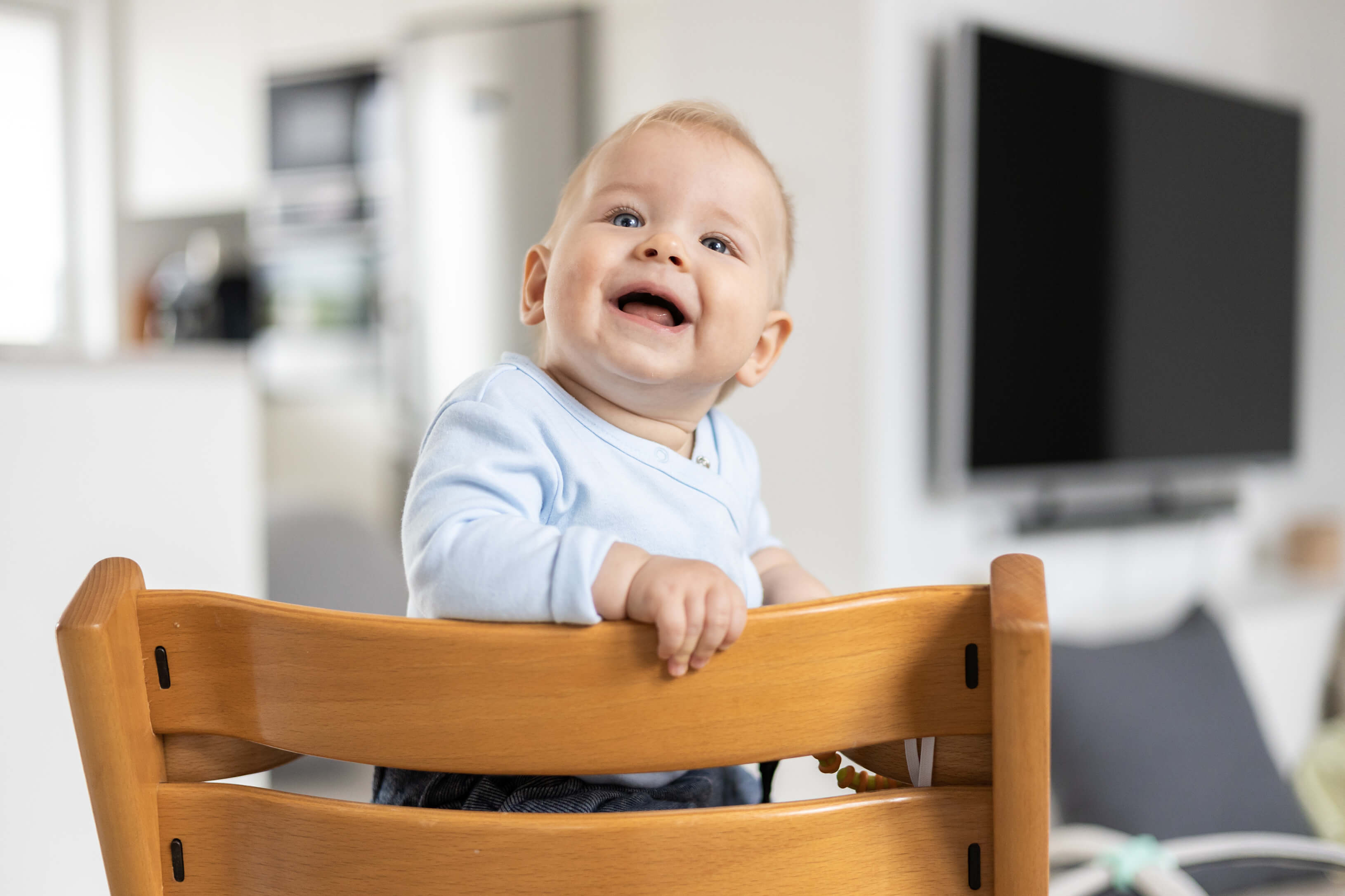 Ein Baby sitzt im Hochstuhl und lacht