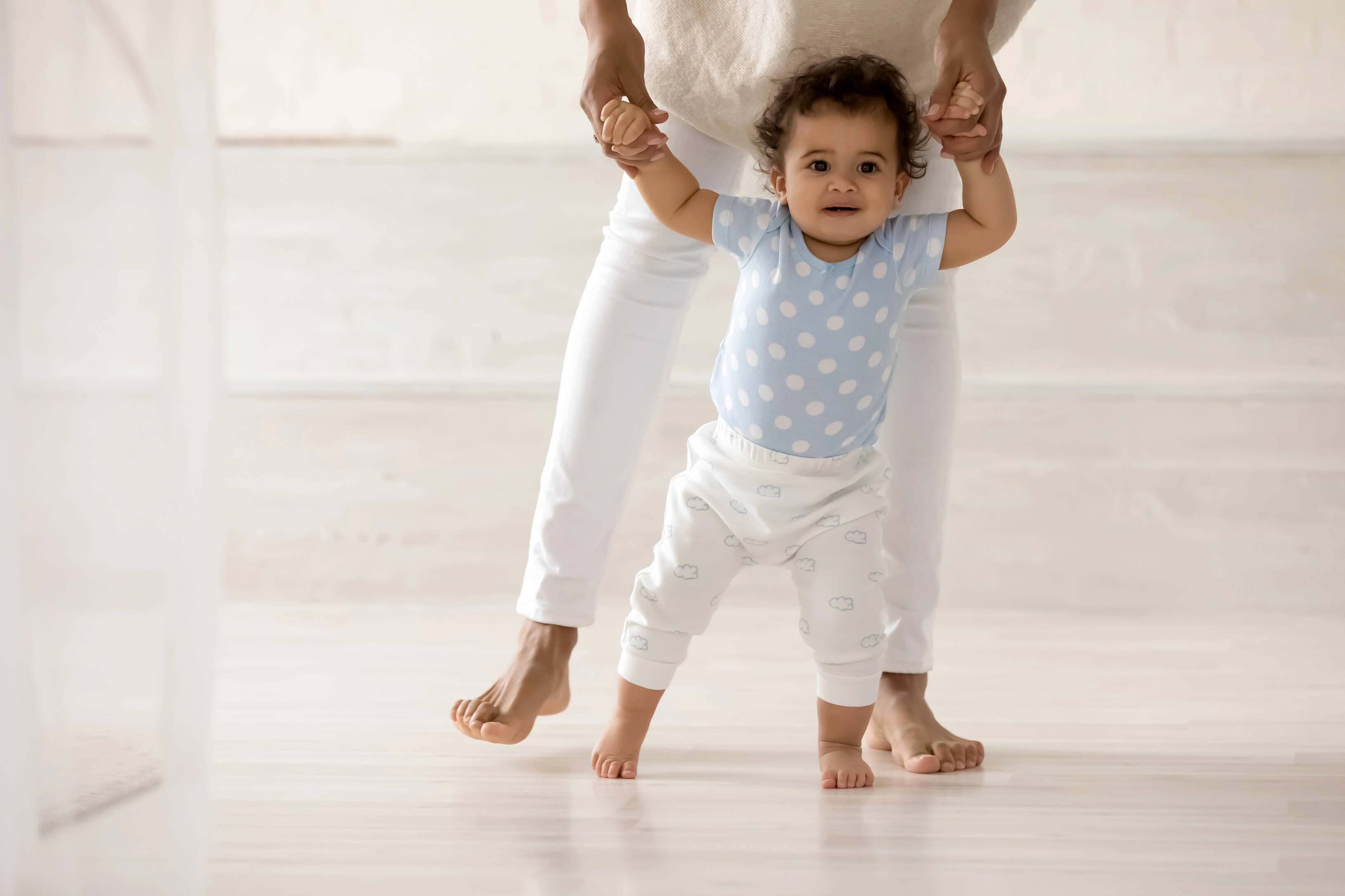 Mutter übt mit Baby das Laufen barfuß